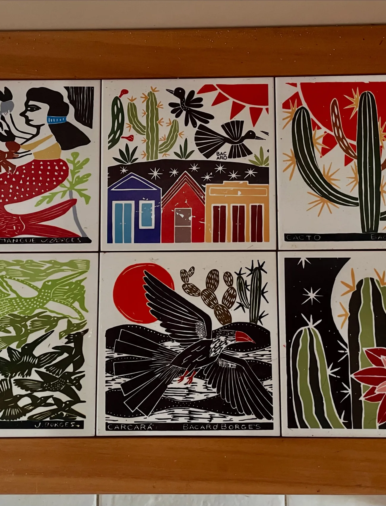 Painel de azulejos com desenhos de pássaros, cactos e casinhas
