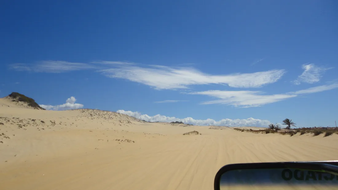 Campo de dunas visto de dentro de um buggy, com rastro de pneu na areia