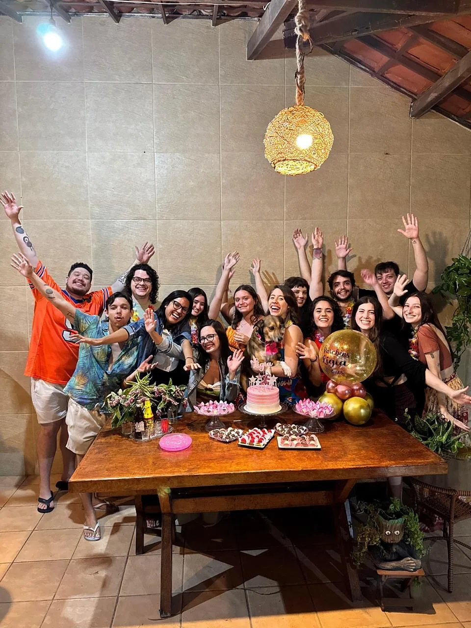 Grupo comemorando em volta da mesa do deck, com a mesa posta e os braços para o alto