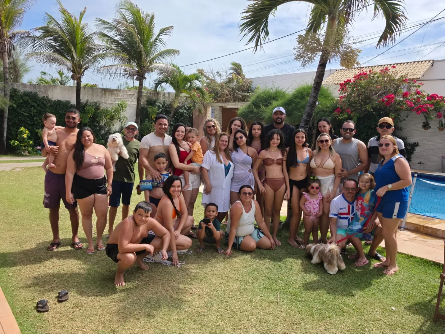 Família grande reunida no gramado em frente à casa