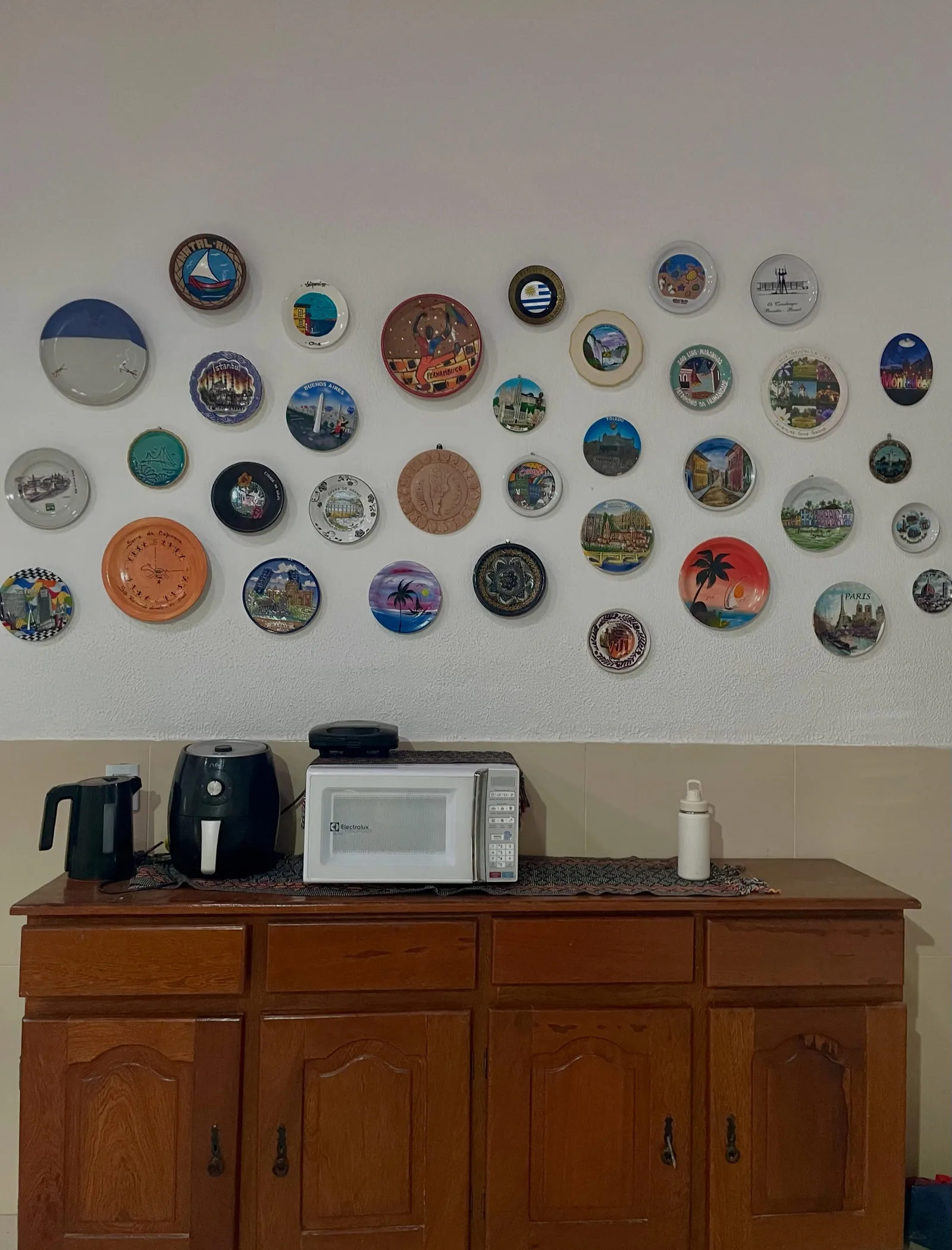 Parede da sala coberta por uma coleção de pratos decorativos trazidos de viagens