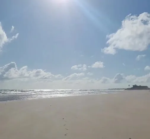 A praia da Caponga com sol alto e o mar ao fundo