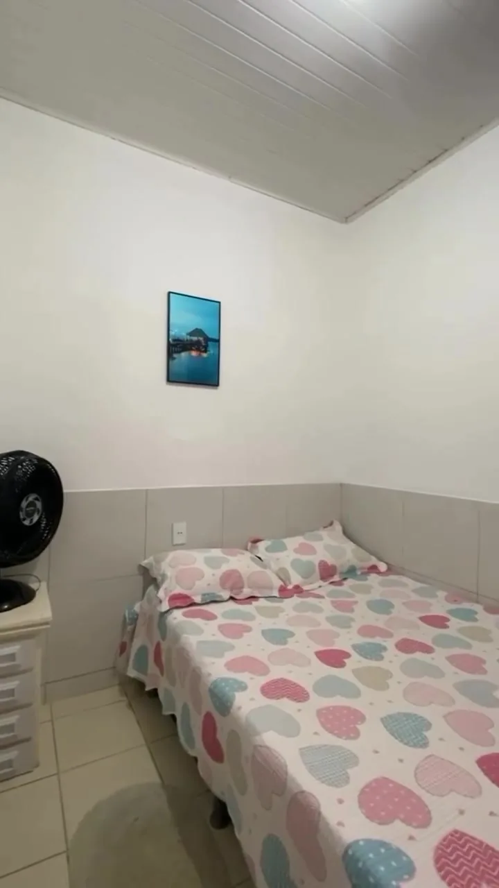 Quarto com cama de casal, colcha estampada e janela de madeira