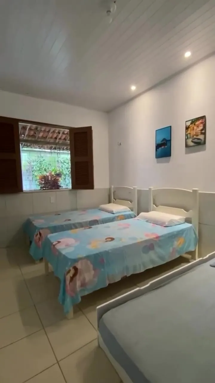 Quarto com três camas e quadros na parede