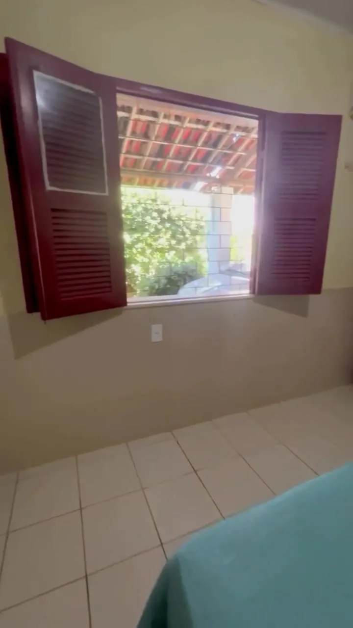 Quarto com janela de madeira aberta para o verde do jardim