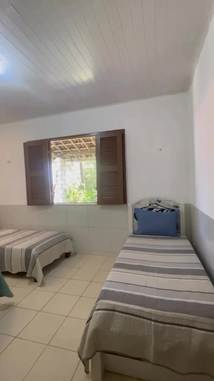 Quarto com três camas de solteiro e colchas listradas